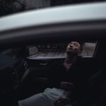young ethnic man sleeping in car