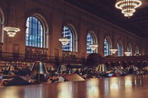 Photo of people in a library with tables and bookcases